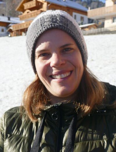Eine Frau mit Hut und Jacke lächelt in die Kamera