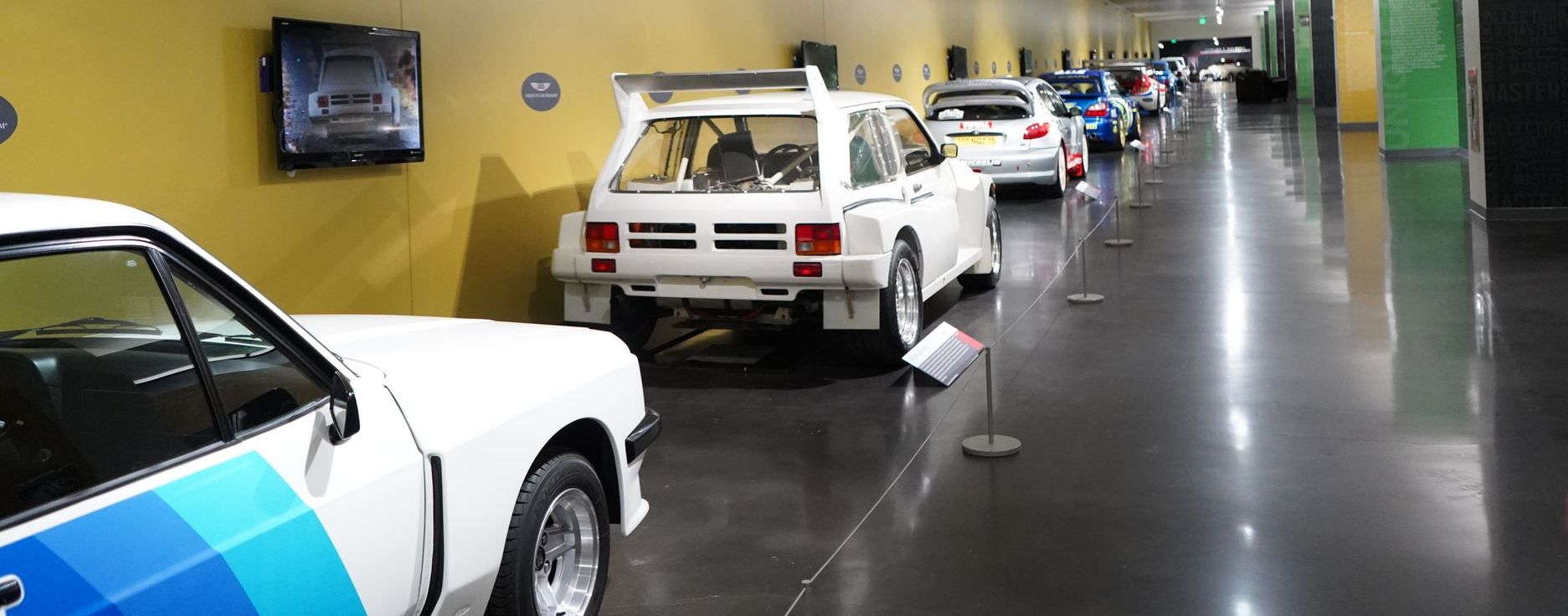 A row of cars and motorcycles are on display in a museum