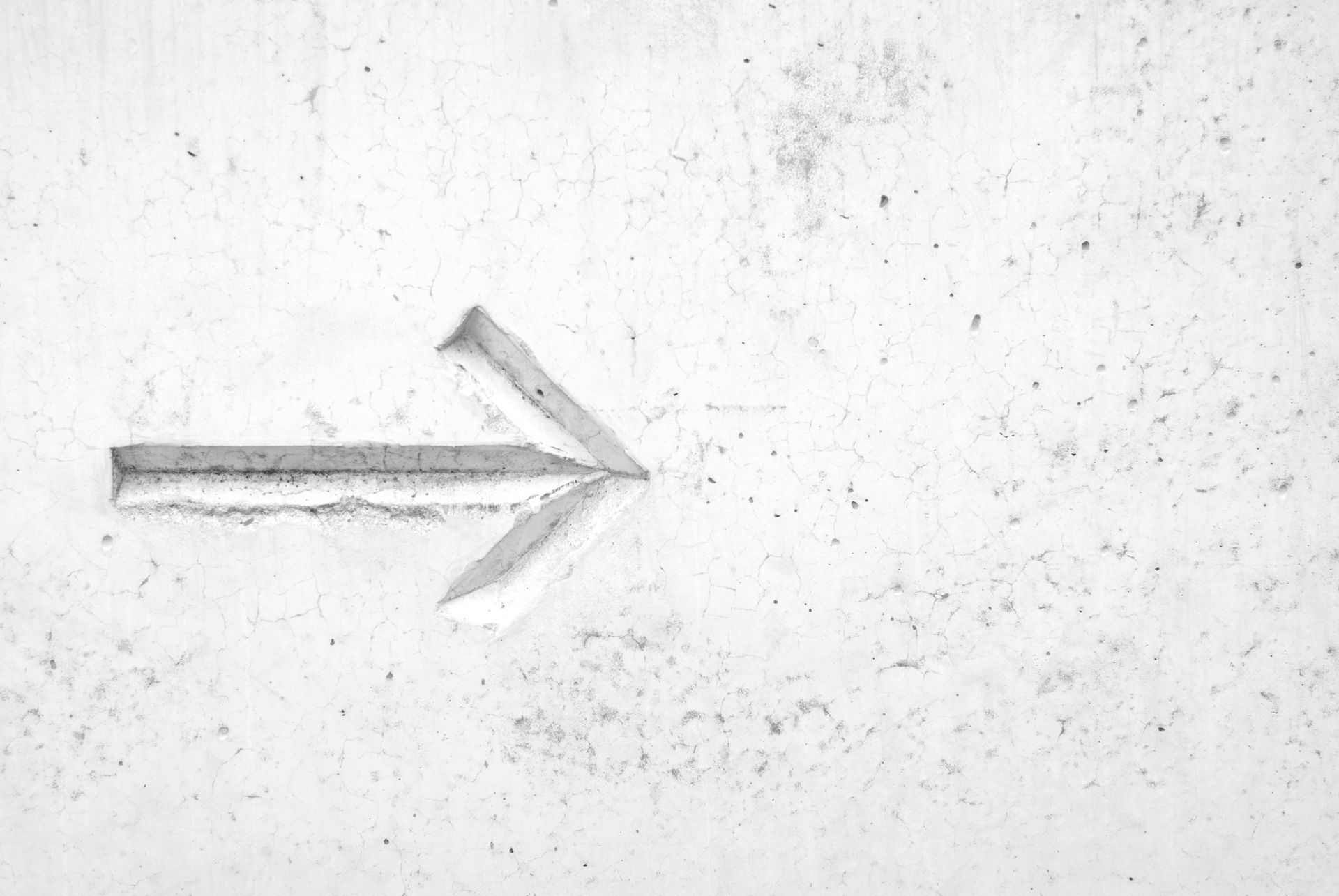 A forward arrow carved in a marble wall.
