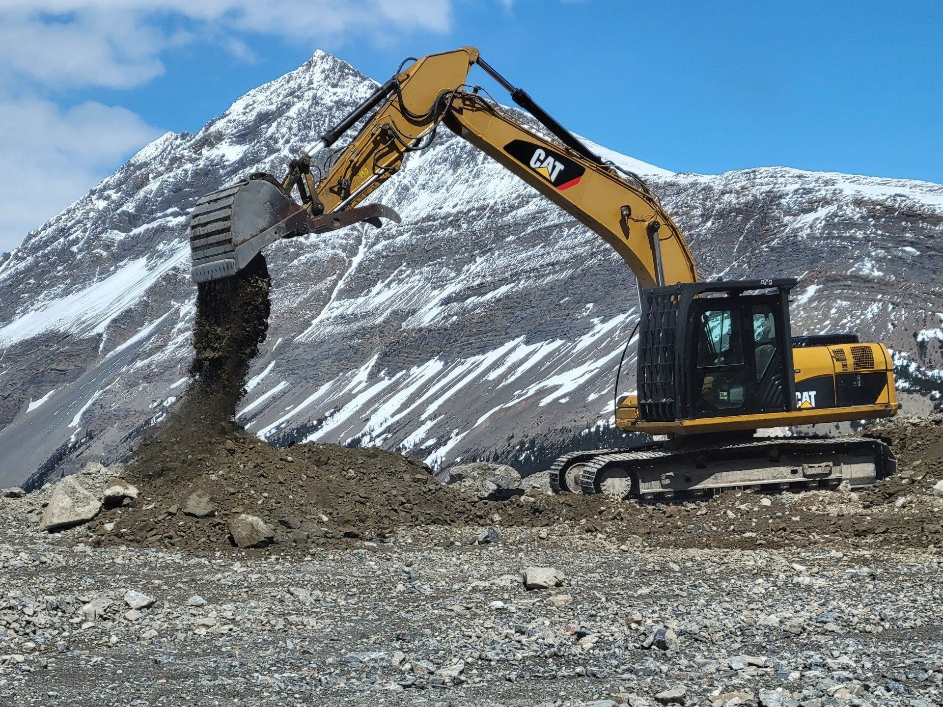 A large excavator releasing it's bucket full of dirt.