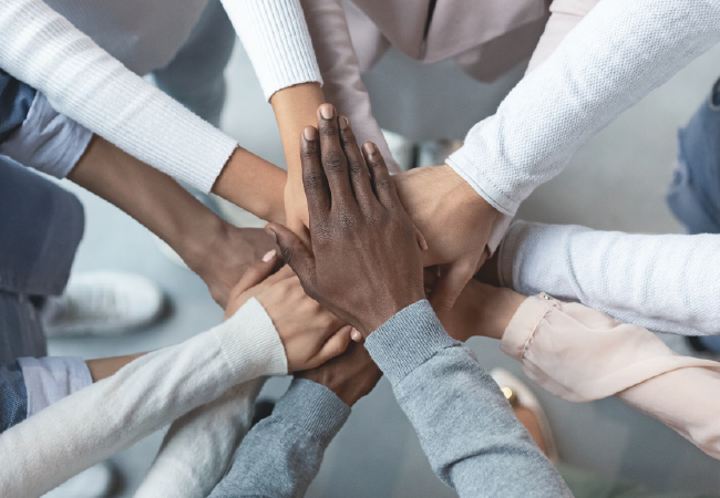 A group of people are putting their hands together in a circle.